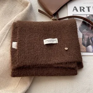 Detail of dark brown wool knit scarf with fluffy texture and white woven label