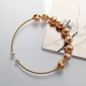 Handmade 14K gold wire wrapped open bangle featuring elegant freshwater champagne pearls