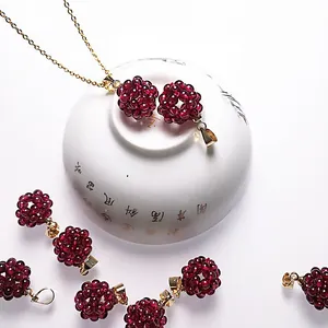 Pendentifs sphériques en perles de grenat rouge foncé avec chaîne dorée sur fond blanc