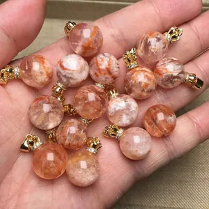 Primer plano de colgantes de piedra solar con detalles dorados sostenidos en la mano