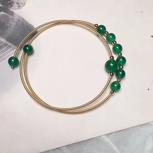 Detailed macro view of 14K gold wire wrapped multi-layer coil bracelet with green agate beads