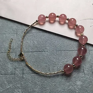 Detailed macro of strawberry quartz beaded bracelet with gold accents and lobster clasp