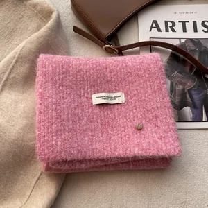 Close-up of pink wool blend knit scarf with woven label and soft fuzzy texture details
