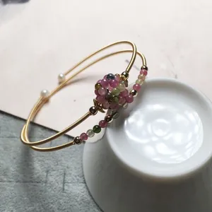 Macro view of multi-layer 14K gold-filled bracelet with tourmaline and pearl beads