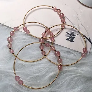 Detail view of 14K gold plated wire wrapped strawberry quartz bracelets set of four