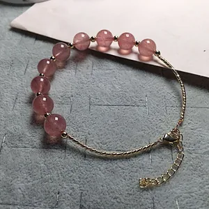 Close-up of strawberry quartz beaded bracelet with gold accents and 14K lobster clasp