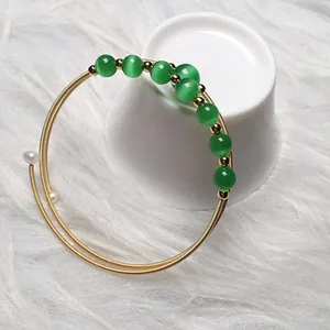 Macro detail of multi-layer 14K gold-filled bracelet with green cat-eye beads and pearls