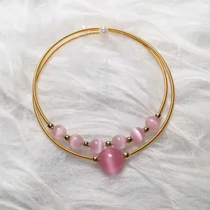 Detail of pink cat-eye stone bracelet with 14K gold wire wrap and white pearl accents