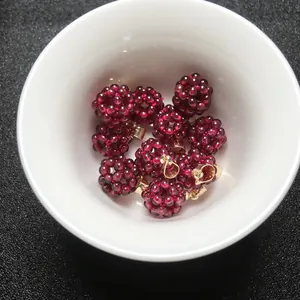 Vue détaillée de pendentifs boules en grenat tissé avec fermoirs dorés dans un bol