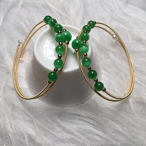 Close-up of 14K gold filled bangles with green cat eye stones and small white pearls