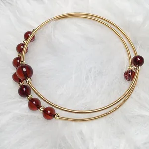 Close-up of golden multi-layer wire wrapped bracelet with red amber beads on white fur
