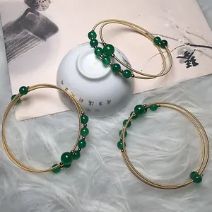 Detail of green agate bead bracelets with 14K gold-filled wire wrap on white faux fur