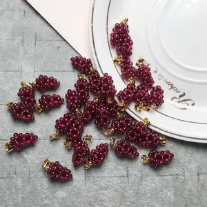 Macro detail of handmade burgundy garnet grape pendants with gold-plated clasps