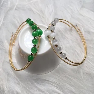 Detail of 14K gold-filled wire wrap bracelets with green and white cat eye stones