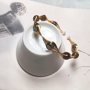 Macro view of handmade wire-wrapped gold bracelet with grey labradorite and small pearls