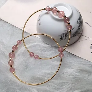 Elegant strawberry quartz 14K gold-filled wire wrapped bracelets on white fur background