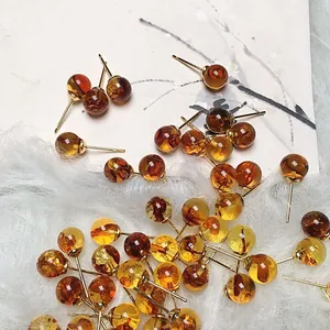 Detalle macro de pendientes de ámbar con pernos chapados en oro 14K en fondo suave