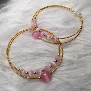 Detail of 14K gold-filled wire wrap bracelet with pink cat eye stones and small pearls