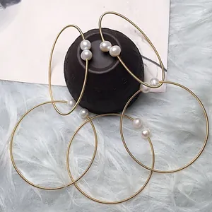 Detail of 14K gold wire wrapped bracelets featuring glossy white freshwater pearls