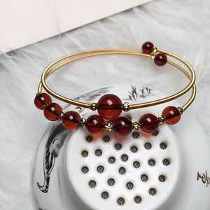 Detailed shot of blood amber double-layer open bangle with 14K gold wire wrap