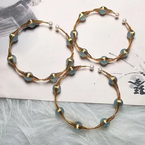 Detailed wire-wrapped gold earrings with blue gemstones and freshwater pearls