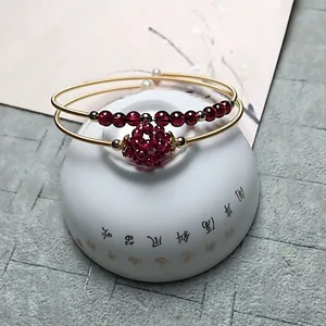 Garnet beaded 14K gold plated bracelets displayed on white porcelain with Zen aesthetic