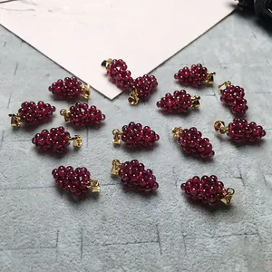 Macro detail of garnet grape pendants with gold-plated clasps on a textured surface