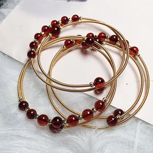 Detailed view of deep red blood amber bracelets with elegant 14K gold wire wrap.