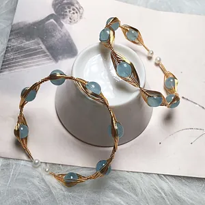 Detail of handmade gold wire wave bracelet with light blue aquamarine and white pearls