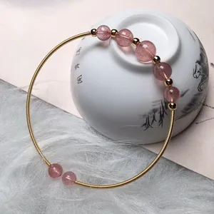 Detailed shot of pink strawberry quartz beads on a 14K gold-filled wire wrap bracelet