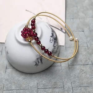 Detail view of 14K gold filled multi-layer open cuff with garnet beads and flower charm