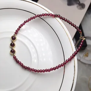Elegant wine red garnet beaded bracelet with 14K gold-filled accents on a ceramic plate