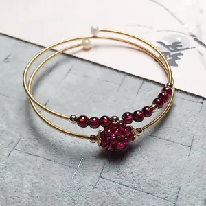 Macro shot of 14K gold filled garnet bracelet with woven beads and pearl details