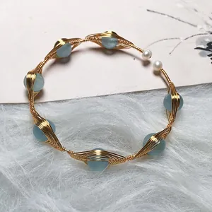 Close-up of handmade gold wire-wrapped bracelet with aquamarine beads and pearls