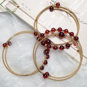 Blood amber bracelet with 14K gold wire wrapped design on elegant white plush background
