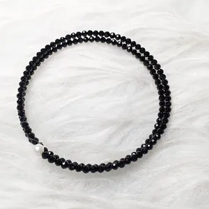 Detailed view of double-layer black faceted spinel beads bracelet with a single white pearl