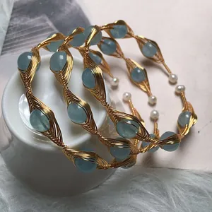 Detail of handmade gold wire-wrapped bracelets with aquamarine beads and pearls