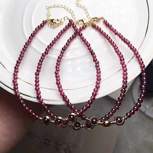 Close-up of three garnet beaded bracelets with 14K gold-filled charms on a white ceramic plate
