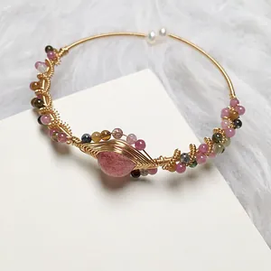 Macro shot of 14K gold wire wrapped strawberry quartz bracelet with pearl details