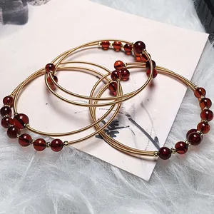 Close-up of three-piece blood amber beaded bracelets with 14K gold-filled spiral wire