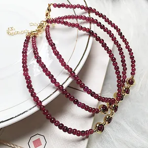 Three-piece set of garnet beaded bracelets with 14K gold-plated clasp on a white plate