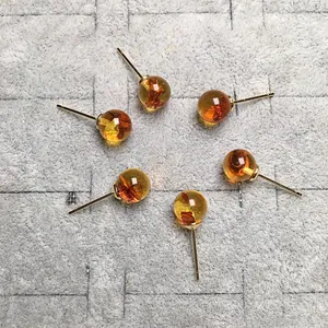 Primer plano de seis pendientes de ámbar y oro de 14K en una bandeja de fieltro gris