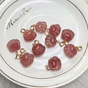 Macro view of strawberry quartz cat paw pendants with gold clasps on a white plate