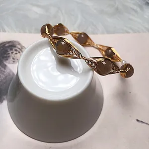 Macro detail of handmade gold wire-wrapped bracelet featuring natural labradorite beads