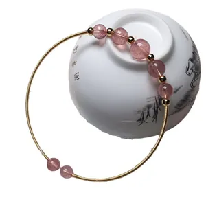 Handcrafted strawberry quartz bangle with 14K gold filled wire wrap on white porcelain