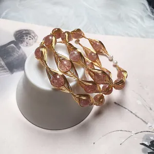 Detail of handmade gold wire-wrapped bracelet featuring strawberry quartz beads and leaf shapes