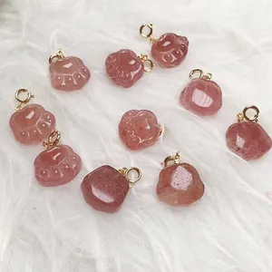 Macro detail of strawberry crystal cat paw pendants with golden metal jump rings