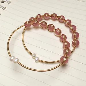 Macro detail of handmade strawberry quartz bangles with 14K gold-filled wire and pearls