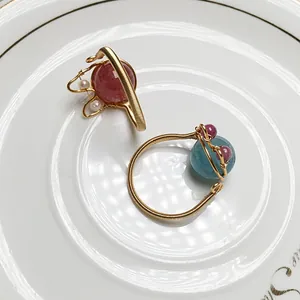 Detailaufnahme handgefertigter 14K Goldringe mit Erdbeerquarz und feiner Drahtwicklung