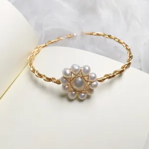 Detail of 14K gold wire hand-wrapped freshwater pearl flower bracelet on a book